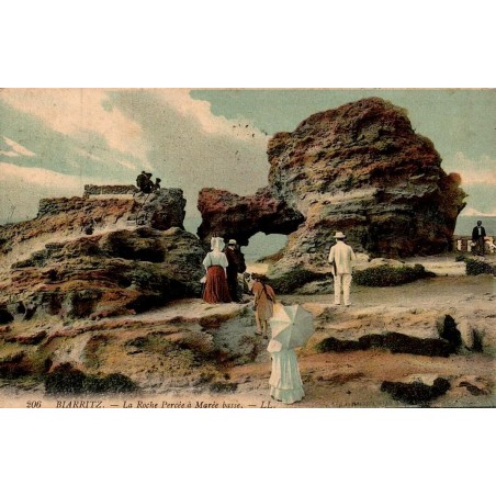 Carte postale ancienne colorisée de Biarritz montrant la Roche Percée à marée basse, voyagée en 1909.