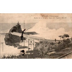 Carte postale ancienne de Biarritz montrant le Rocher de la Vierge et la digue frappée par une vague.