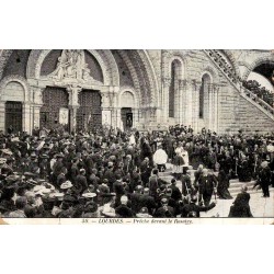 Carte postale ancienne de Lourdes montrant un prêche devant la basilique du Rosaire avec foule de pèlerins.