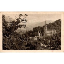 Carte postale ancienne de Lourdes montrant la basilique et les montagnes des Hautes-Pyrénées.
