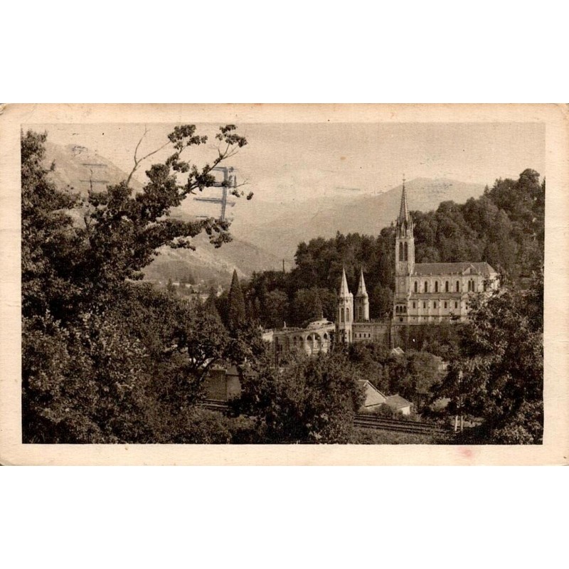 Carte postale ancienne de Lourdes montrant la basilique et les montagnes des Hautes-Pyrénées.