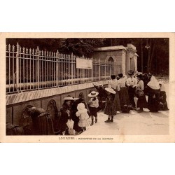 Carte postale ancienne de Lourdes montrant les pèlerins aux robinets de la source de Massabielle.