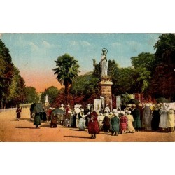 Carte postale ancienne colorisée de Lourdes montrant des pèlerins en prière au pied de la Vierge couronnée.