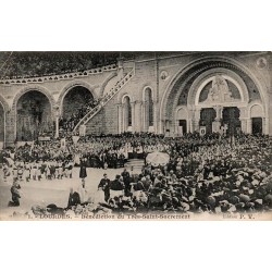 Carte postale ancienne de Lourdes montrant la bénédiction du Très-Saint-Sacrement devant la basilique, voyagée en 1906.