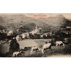 Carte postale ancienne de Lourdes montrant la basilique, les montagnes des Pyrénées et un troupeau de vaches.