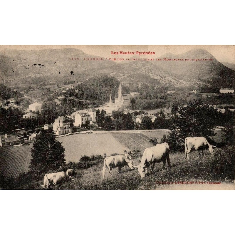Carte postale ancienne de Lourdes montrant la basilique, les montagnes des Pyrénées et un troupeau de vaches.