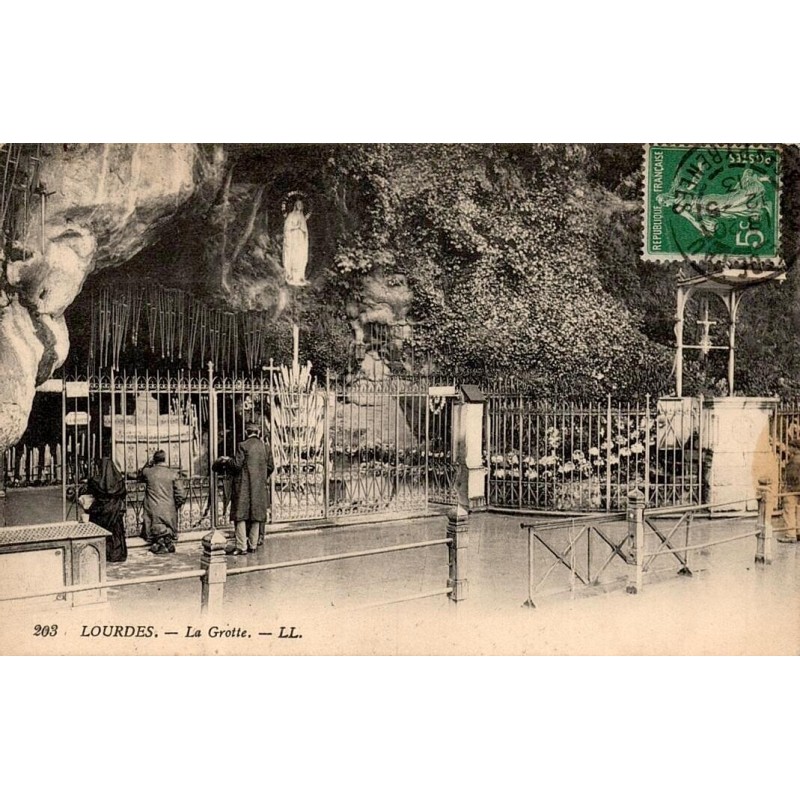Carte postale ancienne de Lourdes montrant la Grotte de Massabielle avec des pèlerins en prière.