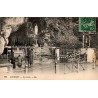 Carte postale ancienne de Lourdes montrant la Grotte de Massabielle avec des pèlerins en prière.