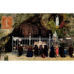 Carte postale ancienne colorisée de Lourdes montrant les pèlerins devant la Grotte de Massabielle.