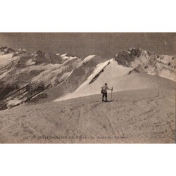 Carte postale ancienne de Superbagnères montrant un skieur face à la chaîne des Pyrénées enneigée.