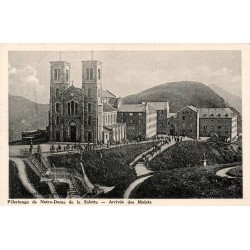 Carte postale ancienne du sanctuaire Notre-Dame de La Salette montrant l'arrivée des mulets devant la basilique.